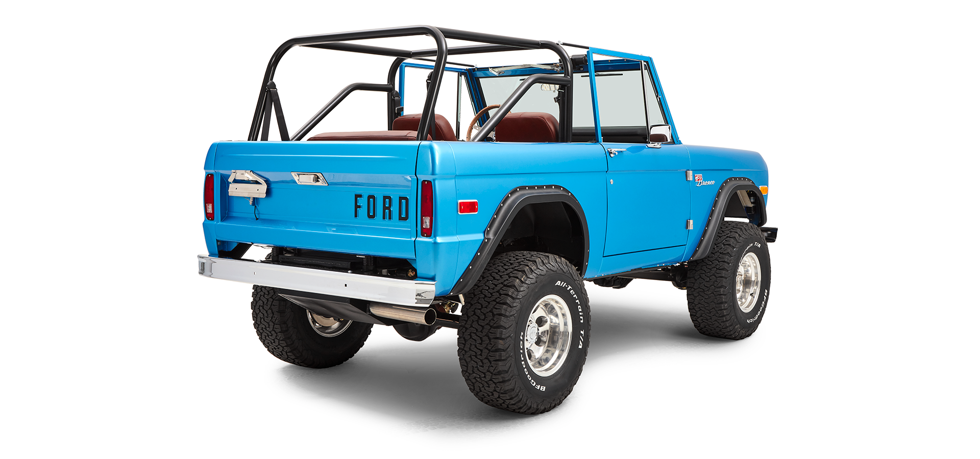 Three-quarter rear view of sky blue Classic Ford Bronco with open roll cage and off-road tires