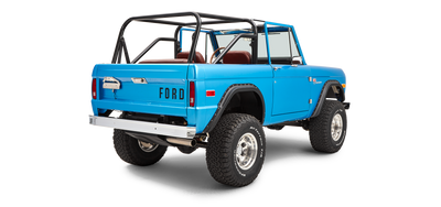 Three-quarter rear view of sky blue Classic Ford Bronco with open roll cage and off-road tires