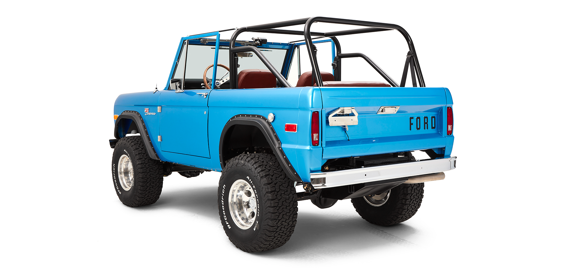 Three-quarter rear view showing passenger side of sky blue Classic Ford Bronco with roll cage and large tires