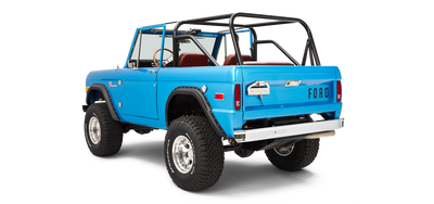 Three-quarter rear view showing passenger side of sky blue Classic Ford Bronco with roll cage and large tires