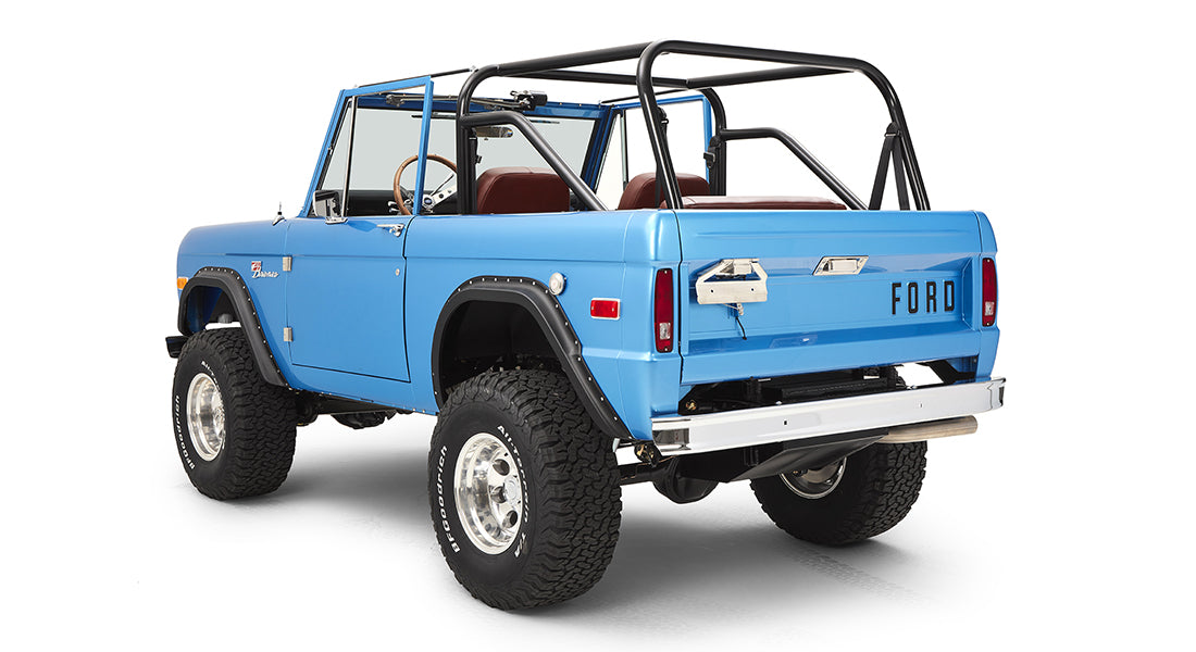 Rear three-quarter view of sky blue Classic Ford Bronco with roll cage isolated on white background