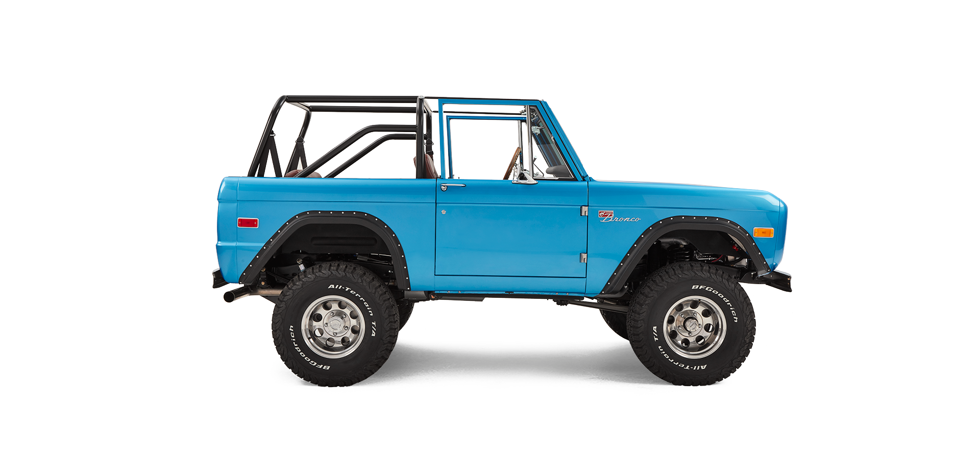 Side profile of sky blue Classic Ford Bronco with open roll cage and off-road tires on white background