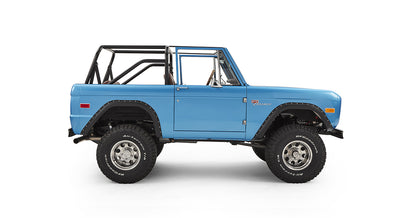 Side view of sky blue Classic Ford Bronco with black roll cage and off-road tires.