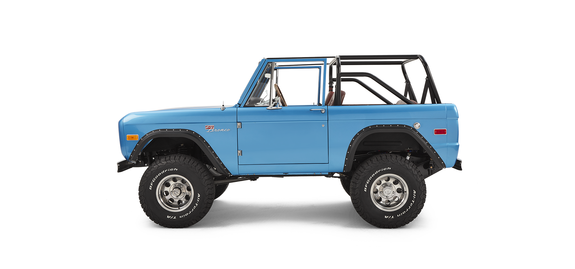 Side profile of sky blue Classic Ford Bronco with open roll cage on white background