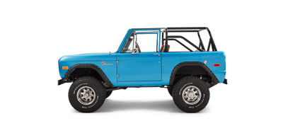 Side profile of sky blue Classic Ford Bronco with open roll cage on white background