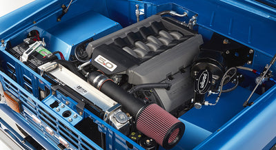 Engine bay of sky blue Classic Ford Bronco showing 5.0-liter engine and polished intake components