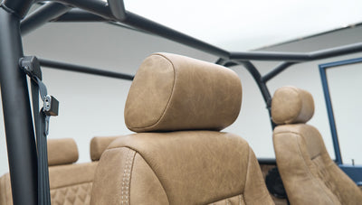 Close-up of the tan leather driver and passenger seats with headrests inside a Classic Ford Bronco.