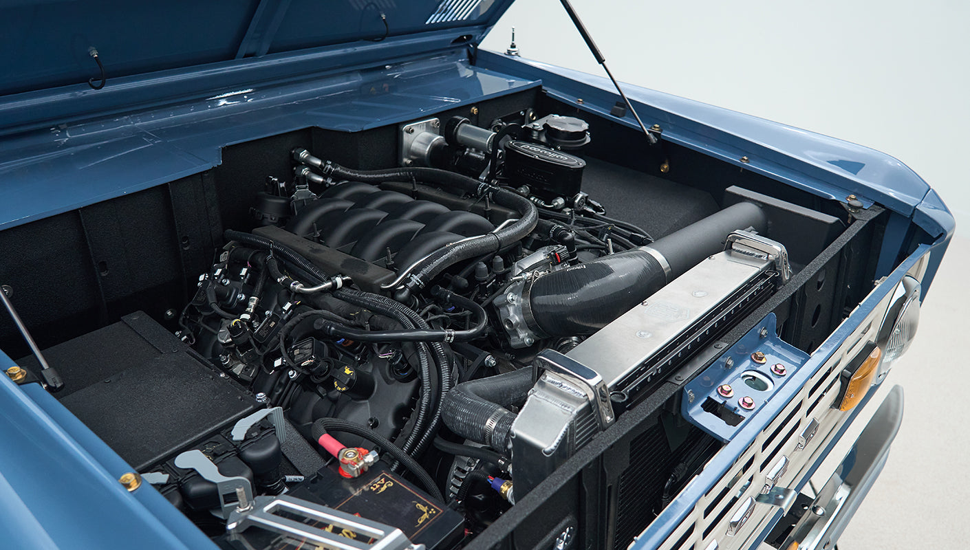 Engine bay of a Classic Ford Bronco showing a modern V8 engine and components.