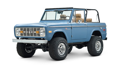 Blue Classic Ford Bronco angled front view showing large off-road tires and open top