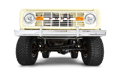 Front undercarriage view of yellow Classic Ford Bronco showing tires and suspension components on white background