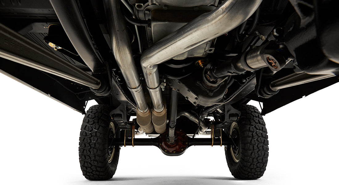 Undercarriage view showing exhaust pipes, axle, and suspension of Classic Ford Bronco