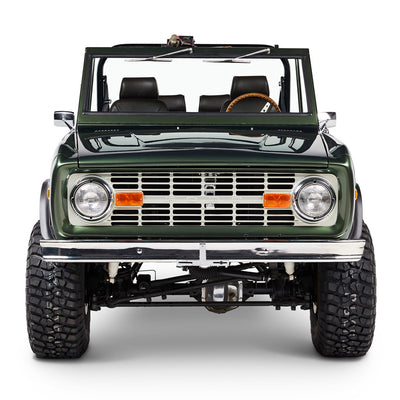 Front view of a green Classic Ford Bronco with visible grill, headlights, tires, and windshield.