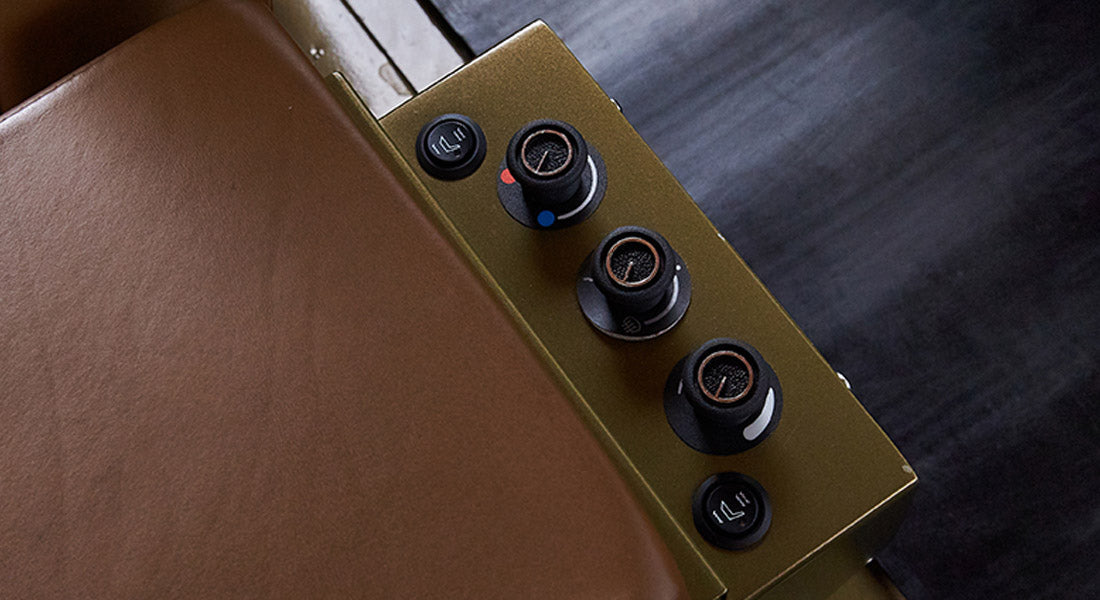 Close-up of seat side panel with three round air control knobs and brown leather seat