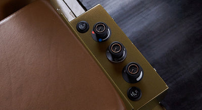 Close-up of seat side panel with three round air control knobs and brown leather seat