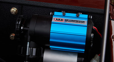 Close-up of blue and black ARB air compressor mounted in engine compartment
