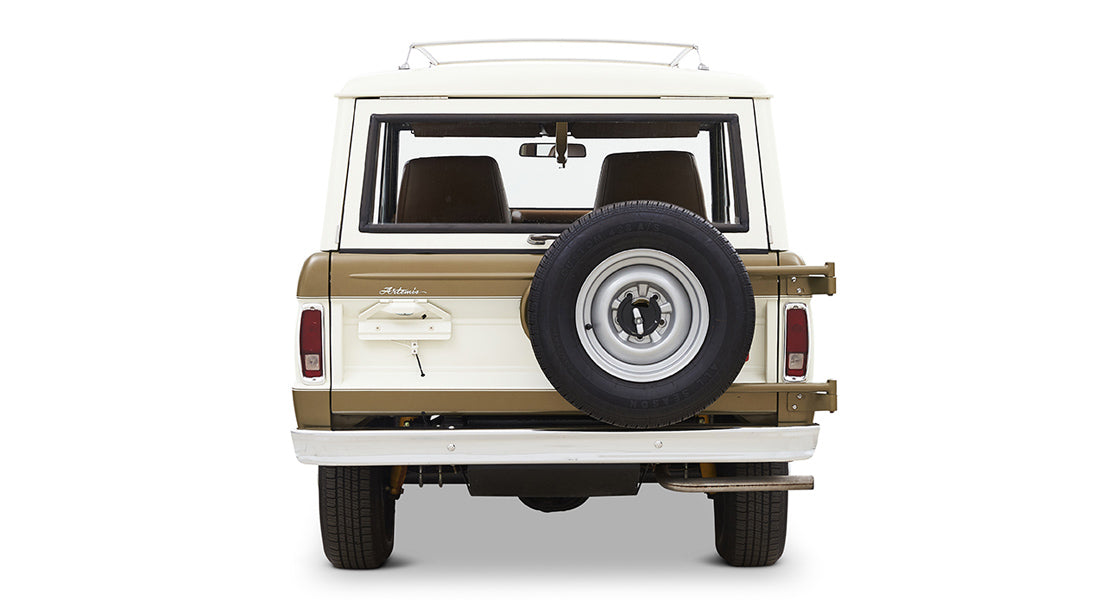 Rear view of a white and brown Classic Ford Bronco with mounted spare tire and tailgate