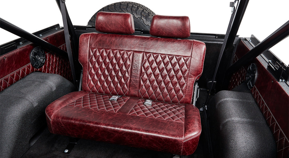 Rear interior bench seat of Classic Ford Bronco upholstered in red diamond-stitched leather.
