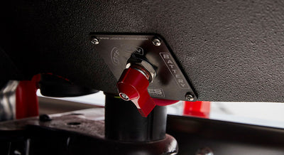 Red battery switch attached to a black panel under the dashboard of a Classic Ford Bronco