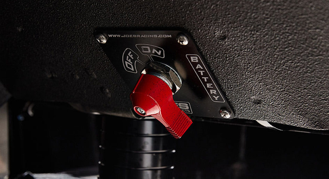 Red battery switch mounted under dashboard in Classic Ford Bronco with labeled metal plate