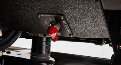 Red battery switch toggle mounted on a black panel inside Classic Ford Bronco