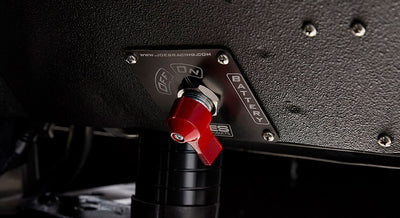 Red battery switch mounted on a textured black panel inside a Classic Ford Bronco