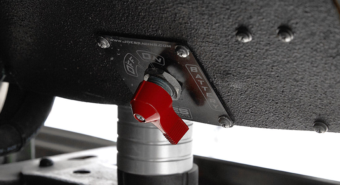 Red toggle battery switch mounted under the Classic Ford Bronco dashboard on a textured black surface.