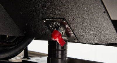 Close-up of a red battery switch mounted on a textured black surface with on/off labels.