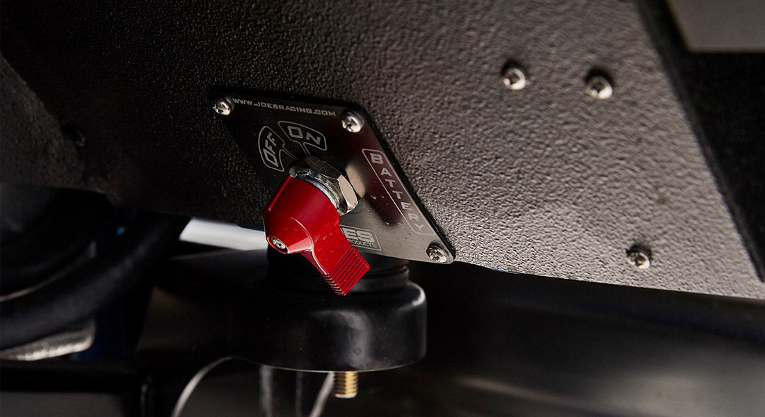 Close-up of battery kill switch with red lever on textured black surface