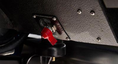 Close-up of battery kill switch with red lever on textured black surface