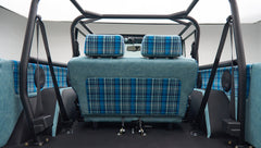 Interior rear seat and side panels of a Classic Ford Bronco in light blue leather and blue plaid fabric