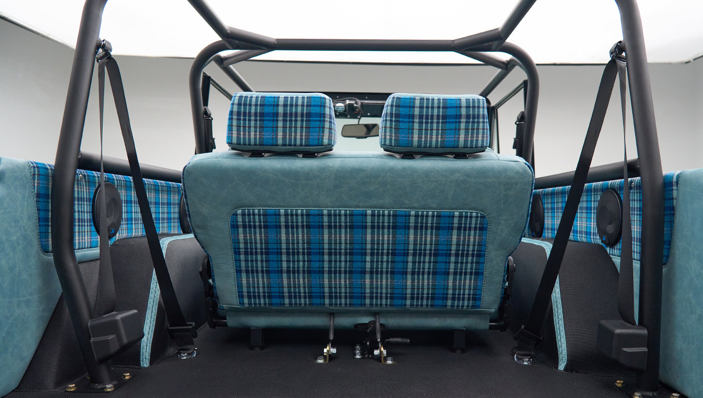 Interior rear seat and side panels of a Classic Ford Bronco in light blue leather and blue plaid fabric