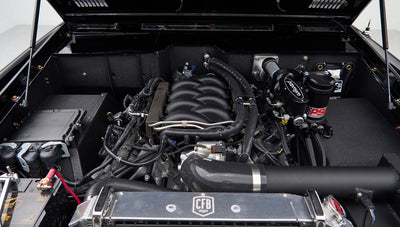Engine bay of a Classic Ford Bronco showing a modern engine with visible hoses and components