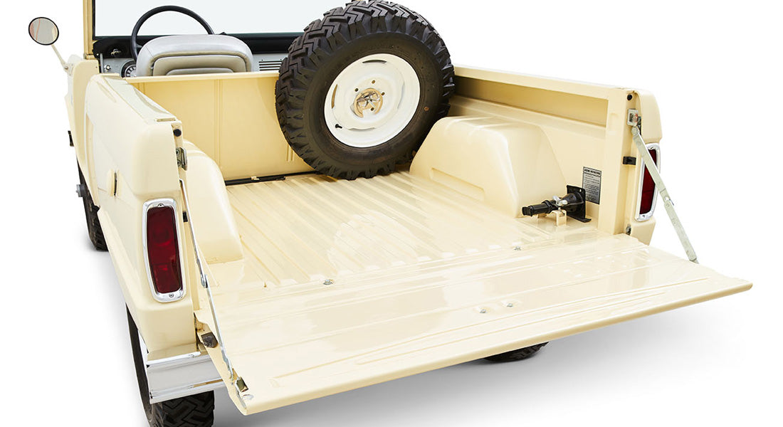 Rear bed of a cream-colored Classic Ford Bronco with tailgate down and spare tire inside