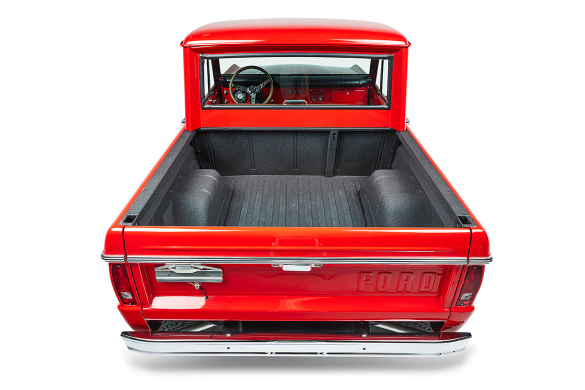Empty bed of a red Classic Ford Bronco with visible interior through rear window