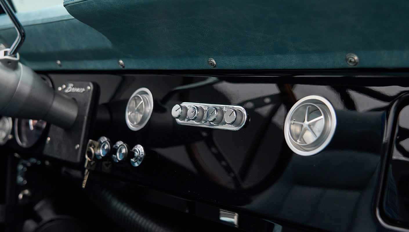 Close-up of Classic Ford Bronco dashboard with black glossy panel and round air vents