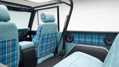 Interior back seats of Classic Ford Bronco with blue plaid fabric and round speakers mounted on side panel
