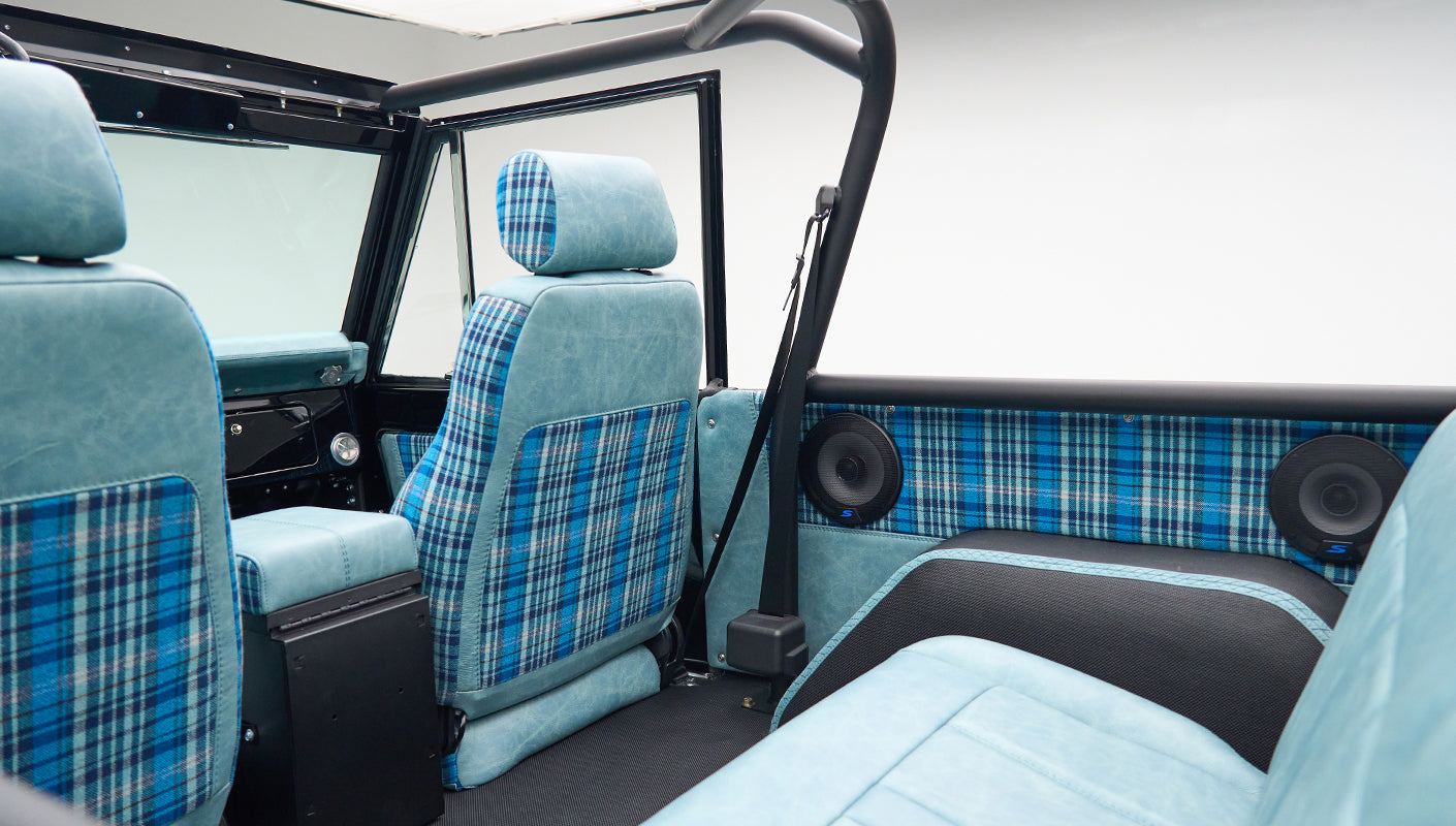 Interior back seats of Classic Ford Bronco with blue plaid fabric and round speakers mounted on side panel
