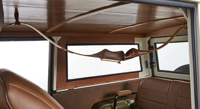 Wooden recurve bow hanging horizontally inside area with brown Classic Ford Bronco interior
