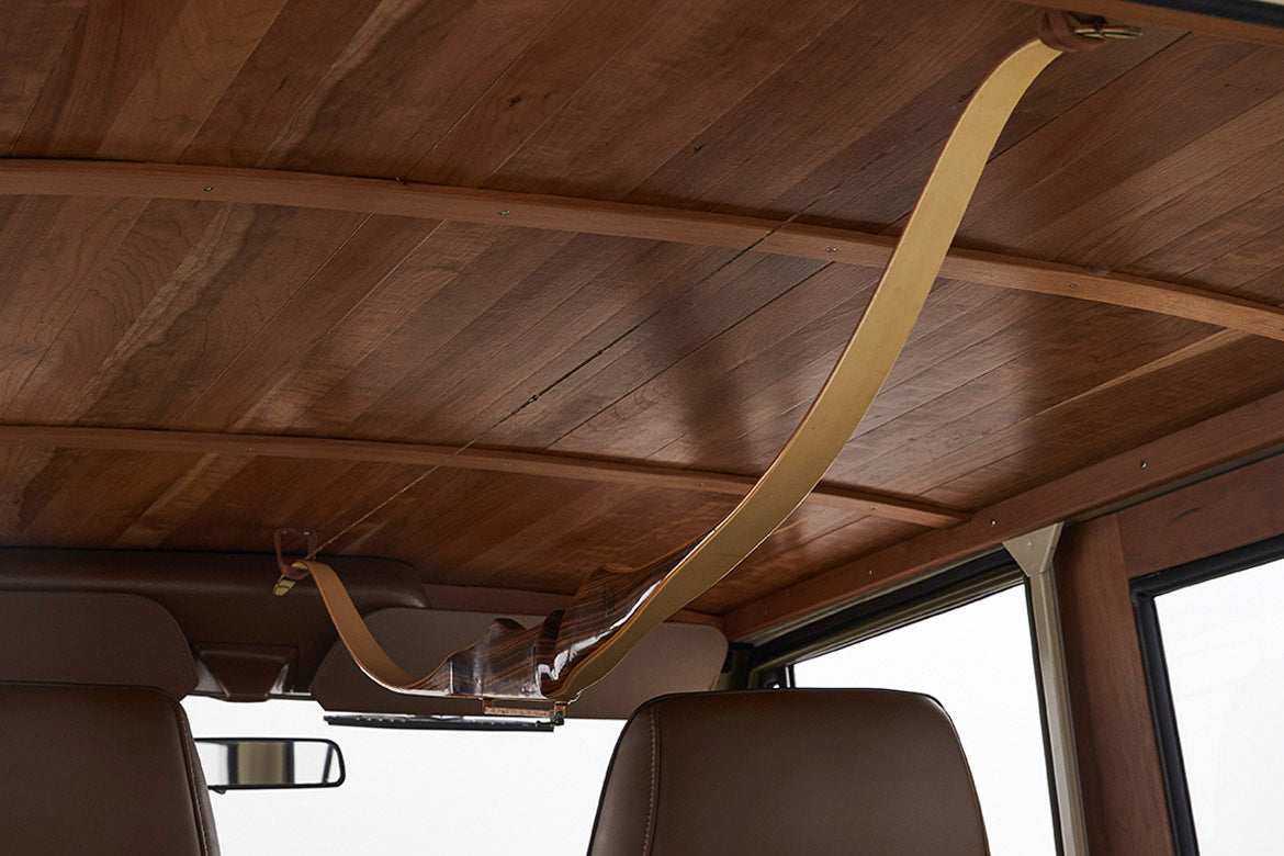 Interior ceiling of Classic Ford Bronco with wood paneling and a mounted wooden bow, front seats visible