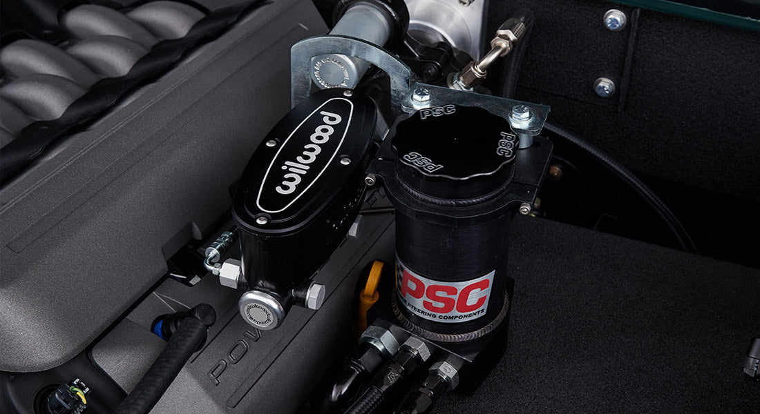 Close-up of Wilwood brake master cylinder and PSC power steering reservoir in Classic Ford Bronco engine bay