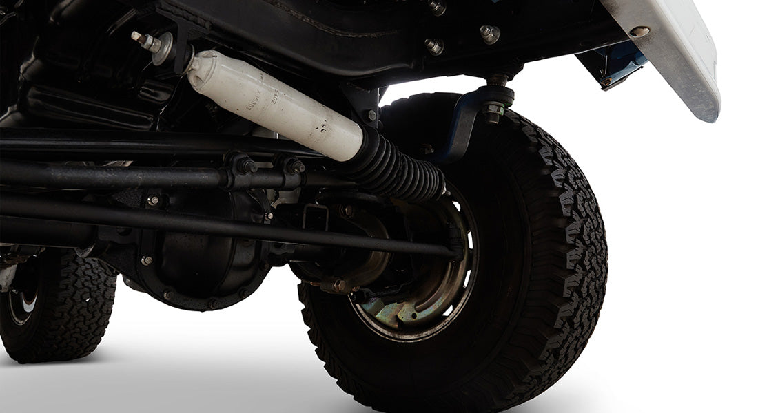 Close-up of Classic Ford Bronco front suspension and steering components with tire.