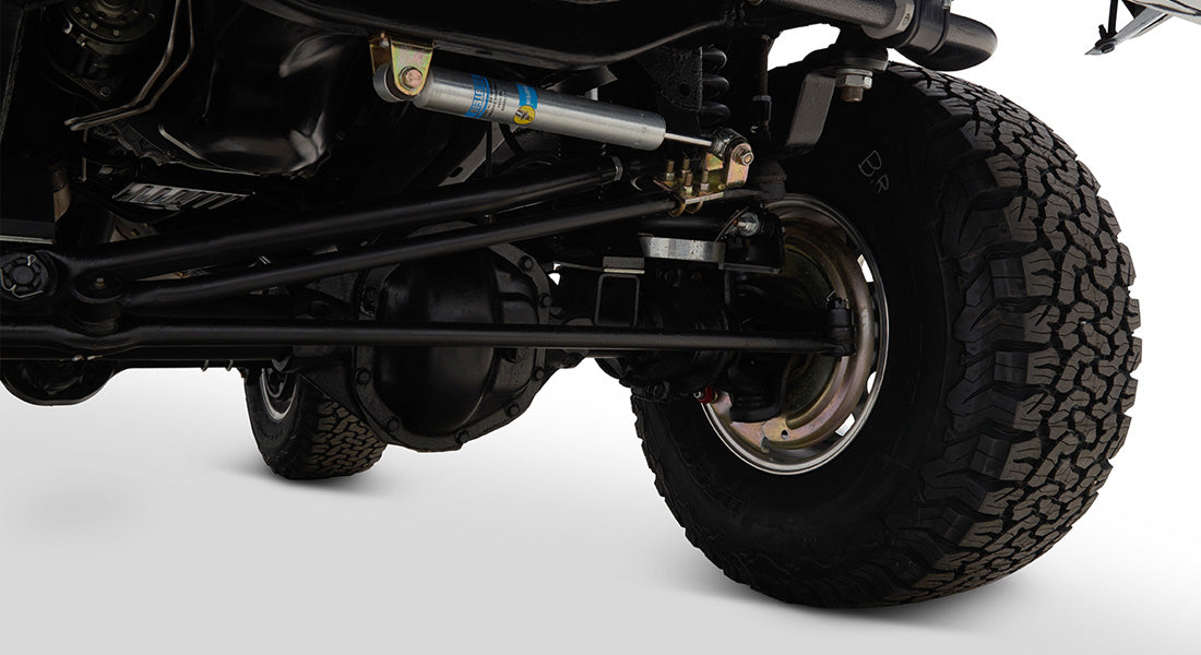 Close-up of Classic Ford Bronco's rear axle and suspension components with tire visible.