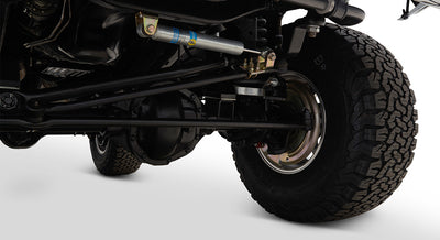 Close-up of Classic Ford Bronco's rear axle and suspension components with tire visible.