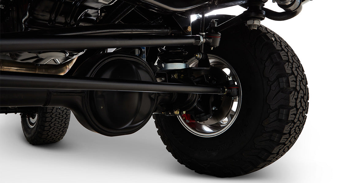 Underside view of vehicle suspension and axle with off-road tire, likely part of a Classic Ford Bronco.