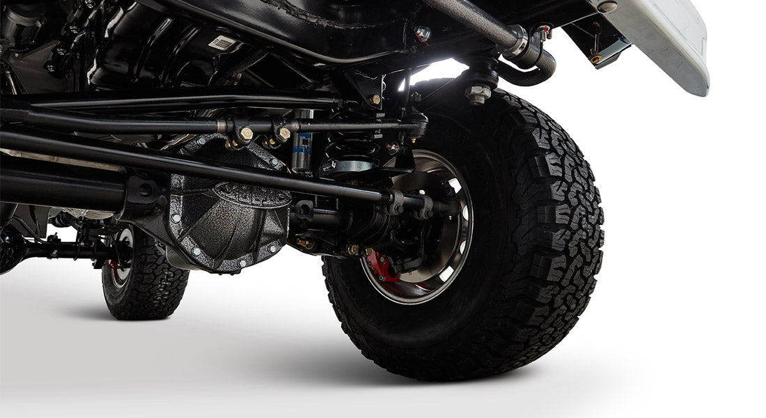 Classic Ford Bronco brake system and front axle visible above a tire against white background