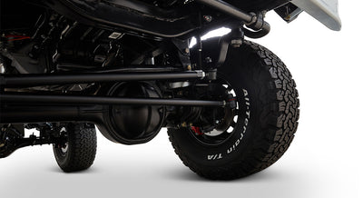 Undercarriage view showing a black axle and suspension parts with an all-terrain tire on a Classic Ford Bronco