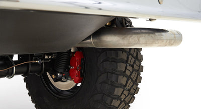 Rear brake assembly with red caliper and large off-road tire under car