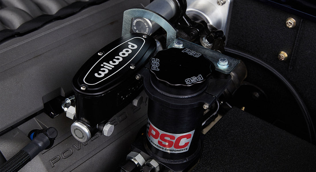 Close-up of power steering components including a reservoir marked PSC and Wilwood part