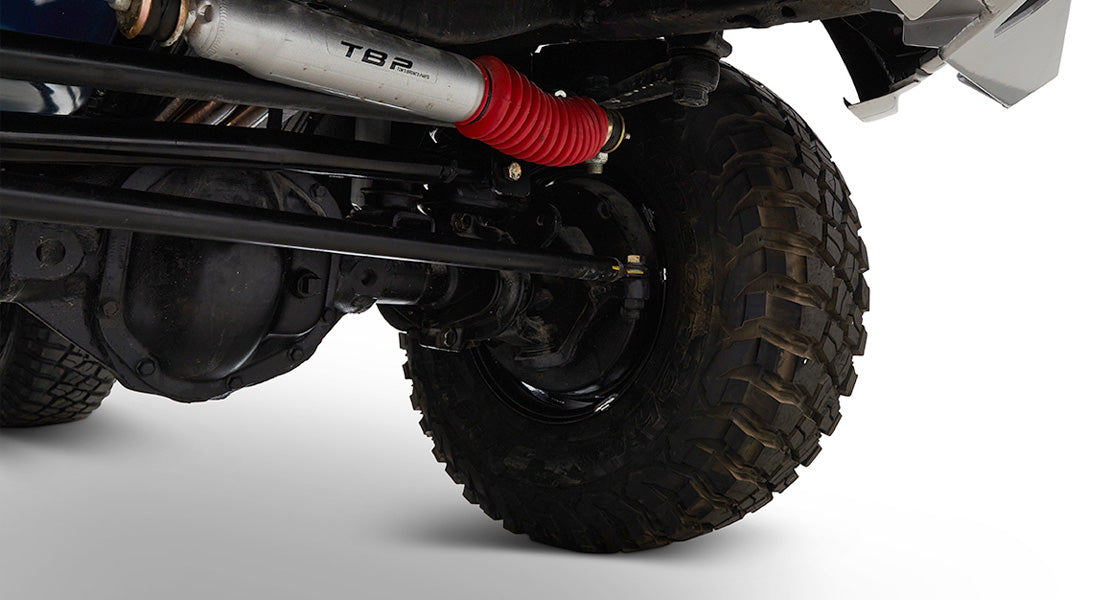 Close-up of off-road tire and suspension components with red shock absorber on Classic Ford Bronco