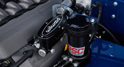 Close-up of a Wilwood brake master cylinder and PSC power steering reservoir in an engine bay